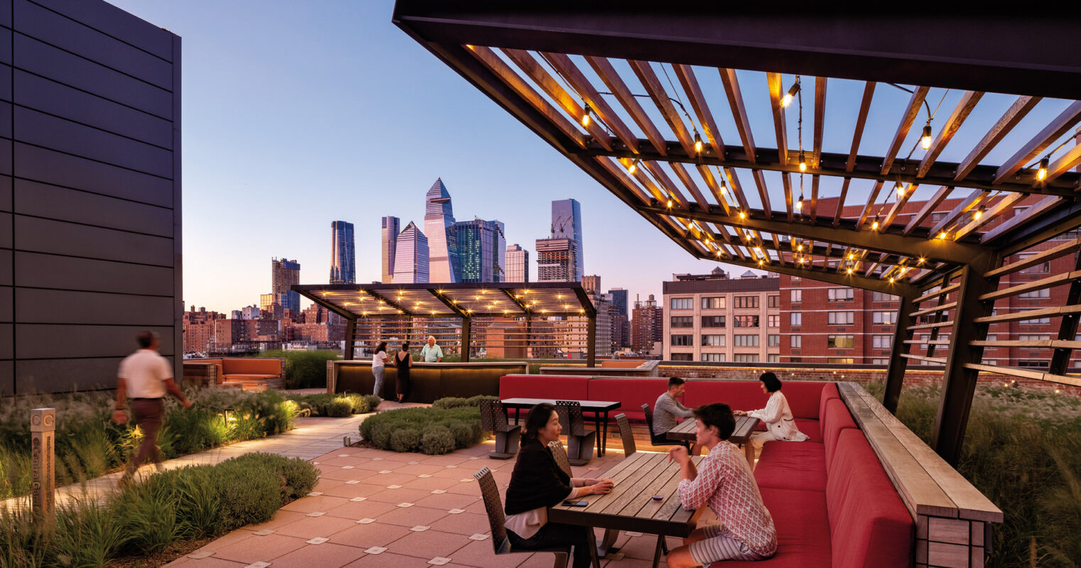 An urban rooftop oasis at dusk, with individuals enjoying conversation around a table, framed by a sleek wooden pergola and the glowing skyline in the background.