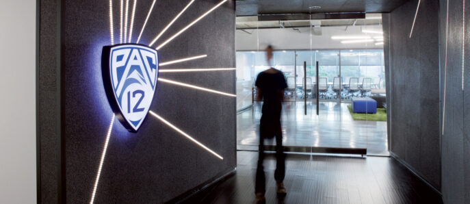 Modern interior with dynamic lighting features leading into a spacious room with glass partitions, showcasing a contrast between sharp geometric lines and a corporate logo illuminated on a textured wall.