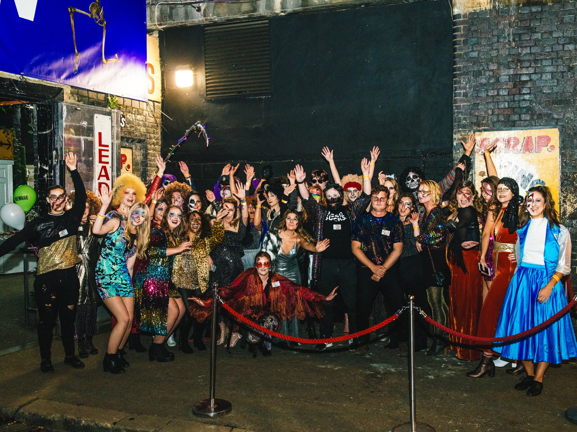 Large group of smiling people in diverse and colorful costumes gathered for a festive event.