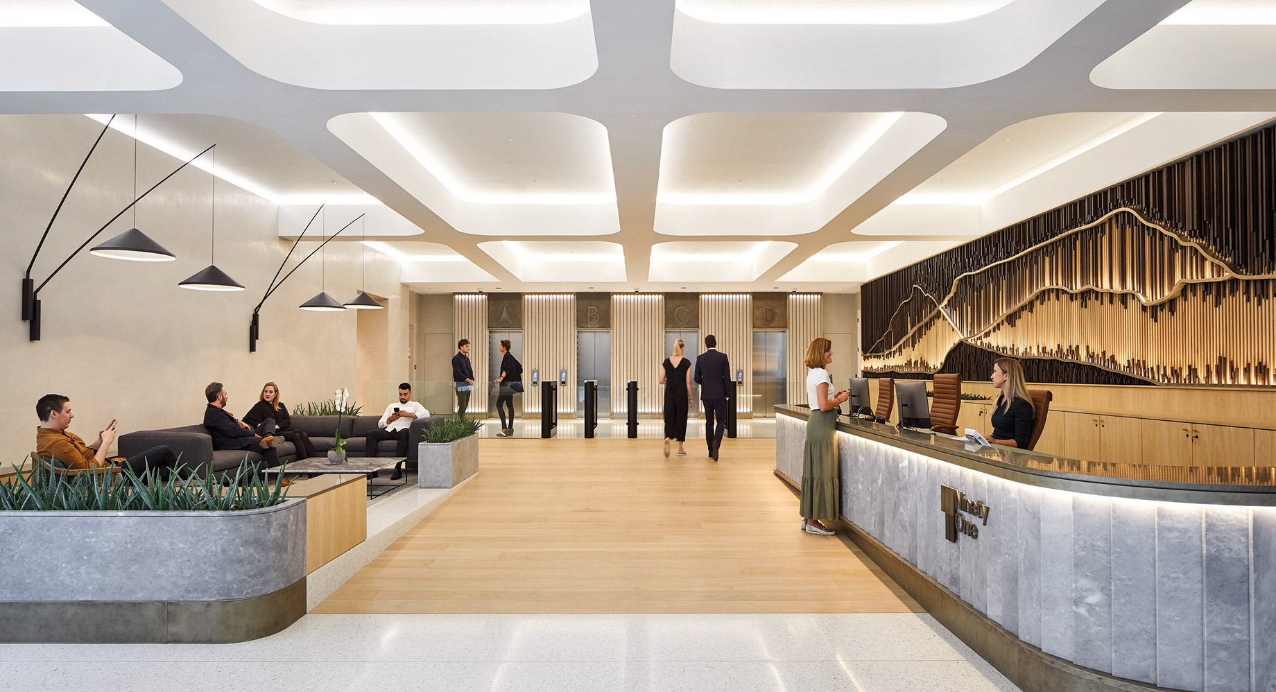 A modern and sleek office lobby with people engaged in various activities, featuring geometric lighting fixtures, wood paneling, and a stylish reception desk.