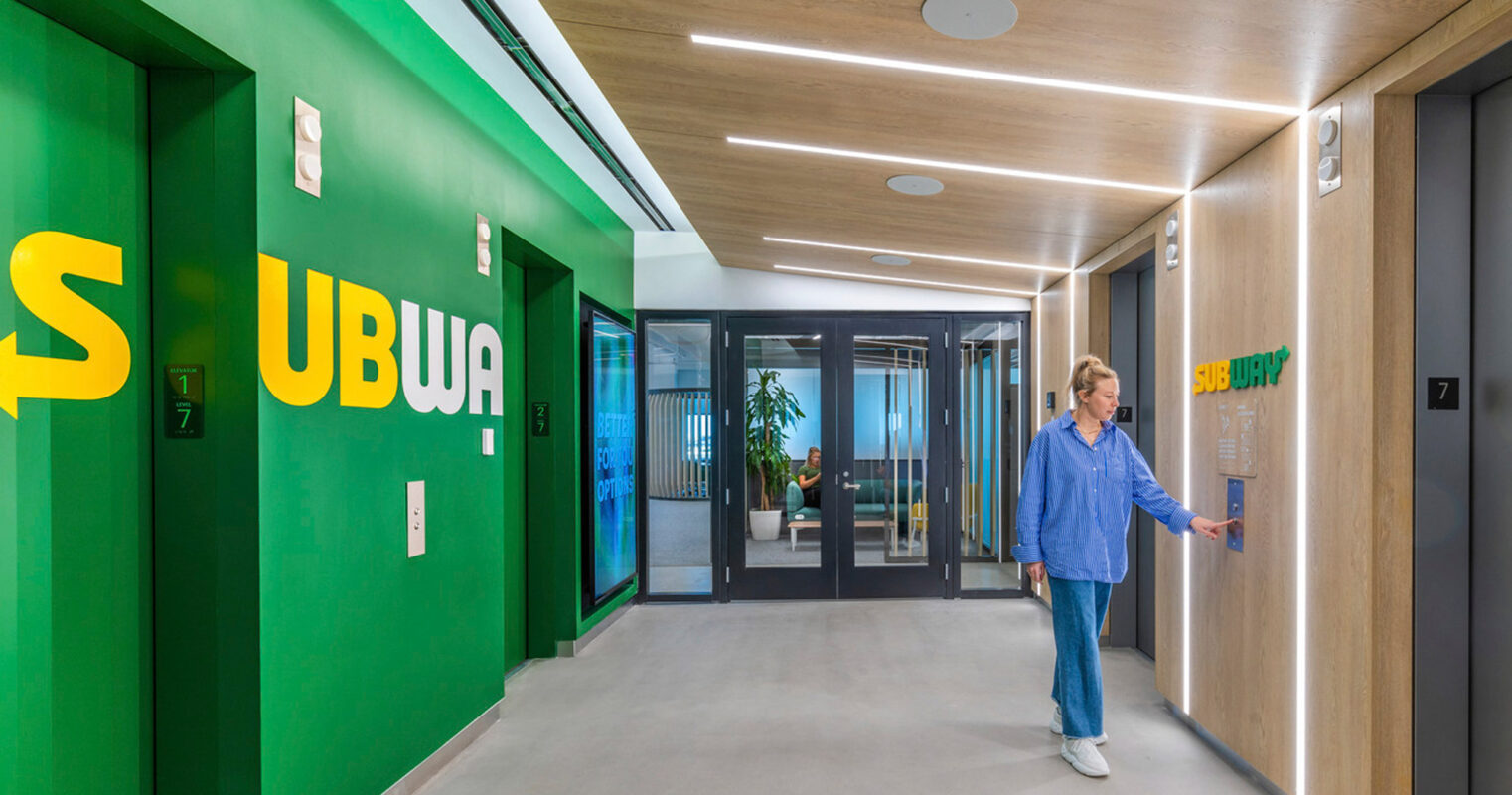 A modern indoor space with a person interacting with a digital interface. The design showcases the seamless integration of technology within contemporary architectural surroundings.