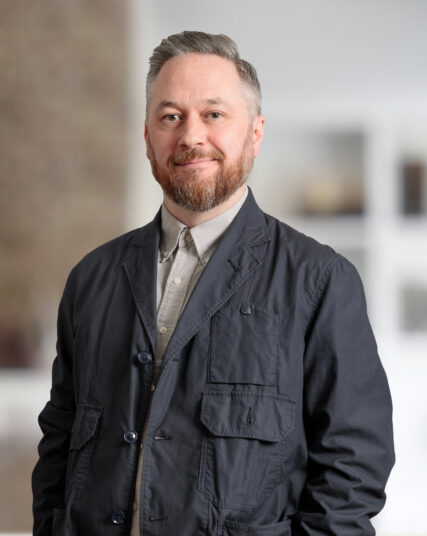 The image depicts a person dressed in casual attire, standing indoors.