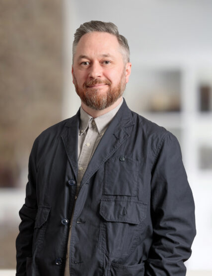 The image depicts a person dressed in casual attire, standing indoors.