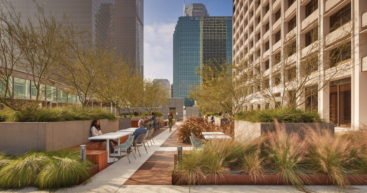 Urban oasis: office workers enjoy a peaceful break amidst lush planters and modern seating in the heart of the city's towering skyscrapers.