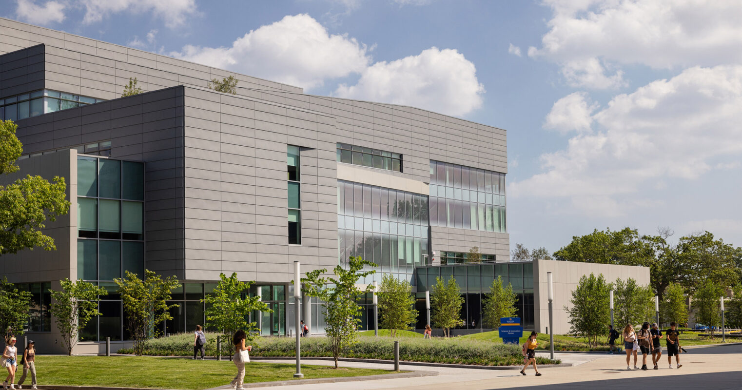Modern educational building featuring clean lines, expansive glass facade for natural lighting, and aluminum composite panels. Landscaped with young trees and pedestrian pathways, the design encourages student engagement and environmental harmony.