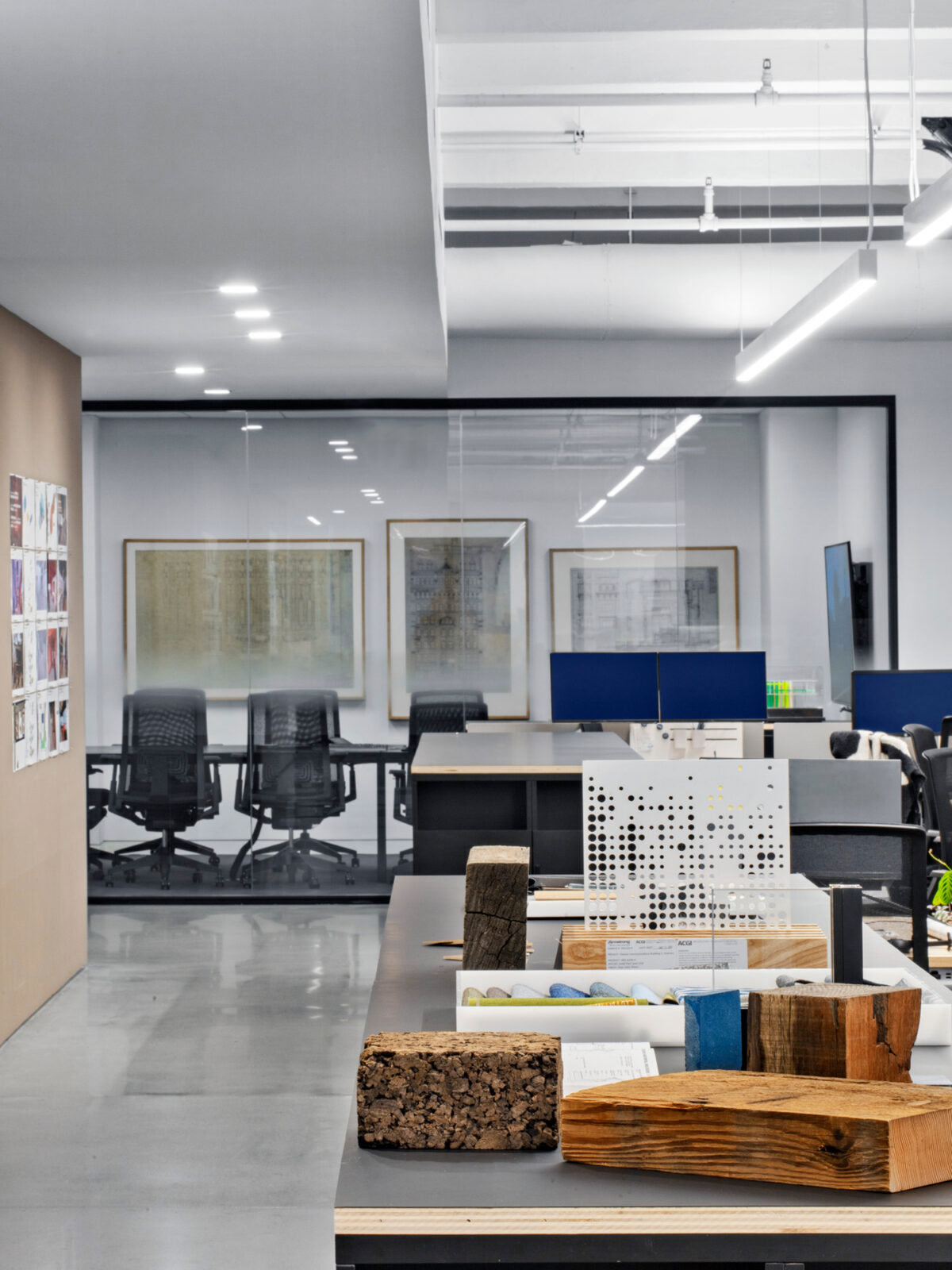 An open-concept office space with a mix of materials and textures on display, including wood, cork, and perforated metal, paired with sleek furniture, creating a creative and tactile material library.