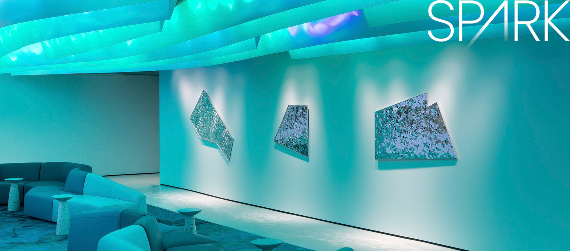 A modern office lounge area illuminated with neon blue lights featuring sleek furniture and abstract art installations.