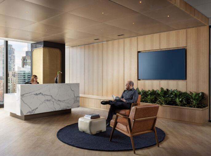 Minimalist office lobby featuring a sleek white marble reception desk, warm wooden wall panels, and a cozy seating area with a leather armchair, complemented by natural greenery and expansive city views through floor-to-ceiling windows.