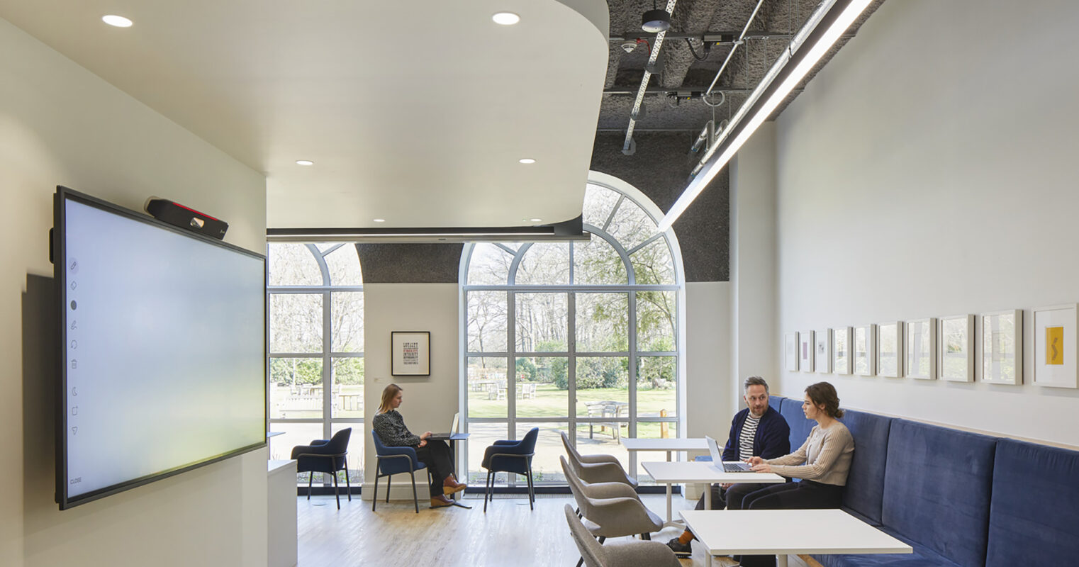 Bright and modern space featuring a stylish combination of curved lines and angular shapes. Elegant seating areas are complemented by large windows, allowing natural light to flood the room. Minimalistic furniture in soft colors enhances the contemporary atmosphere, fostering collaboration and comfort in a professional environment.