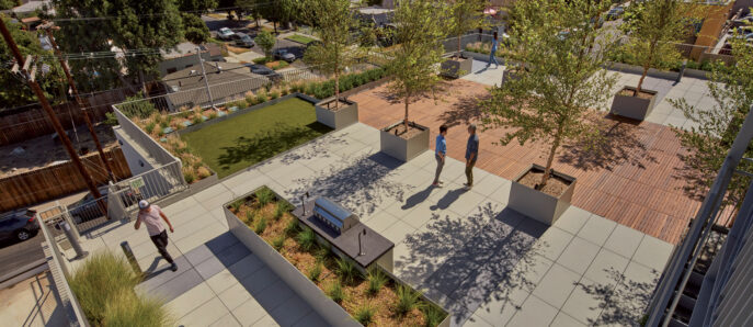 Rooftop terrace features modular seating and lush plantings, optimizing urban space with a green area and walkways, amidst a backdrop of cityscape and palm trees.