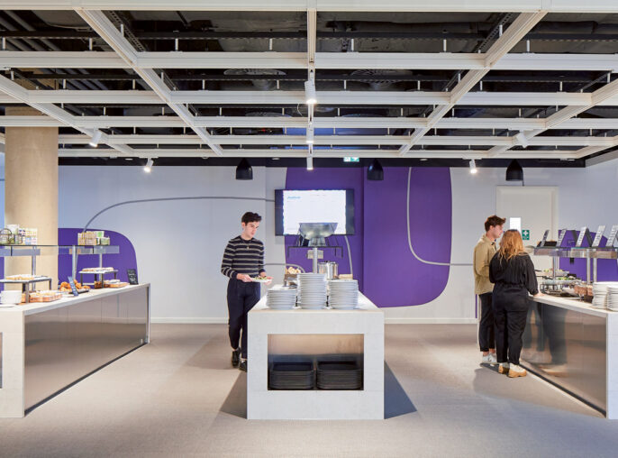 Modern office cafeteria with exposed ceiling, featuring sleek white furniture and vibrant purple accent walls. The space is well-lit, promoting a clean and energizing atmosphere for break-time refreshment.