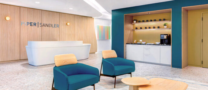 Modern reception area with curved white desk, accented by teal armchairs and wooden stools. A blue alcove with shelving hosts refreshments, set against a warm wooden backdrop with the company’s signage. Ambient lighting complements the room's clean, inviting aesthetic.