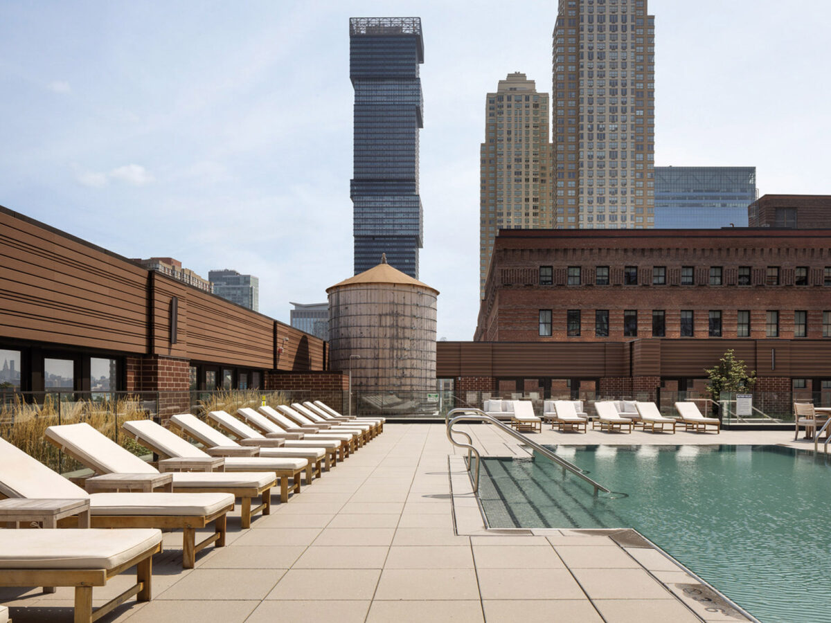 Rooftop pool surrounded by wooden deck chairs, with a clean, modern design, showcasing the skyline view, highlighting urban luxury living.