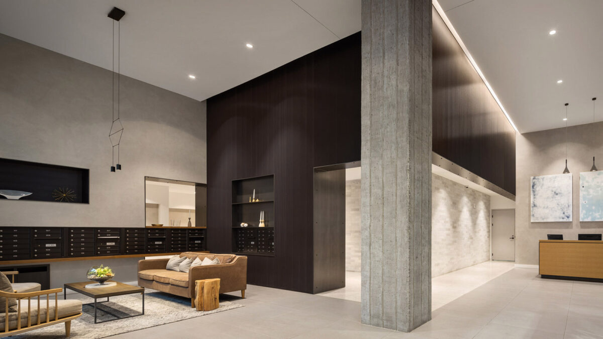 Contemporary living room featuring a neutral color palette, with clean lines, recessed lighting, and a mixture of wooden and concrete textures. Central support column echoes the room's minimalist aesthetic. Plush sofa and armchairs offer seating arranged around a rectangular coffee table.