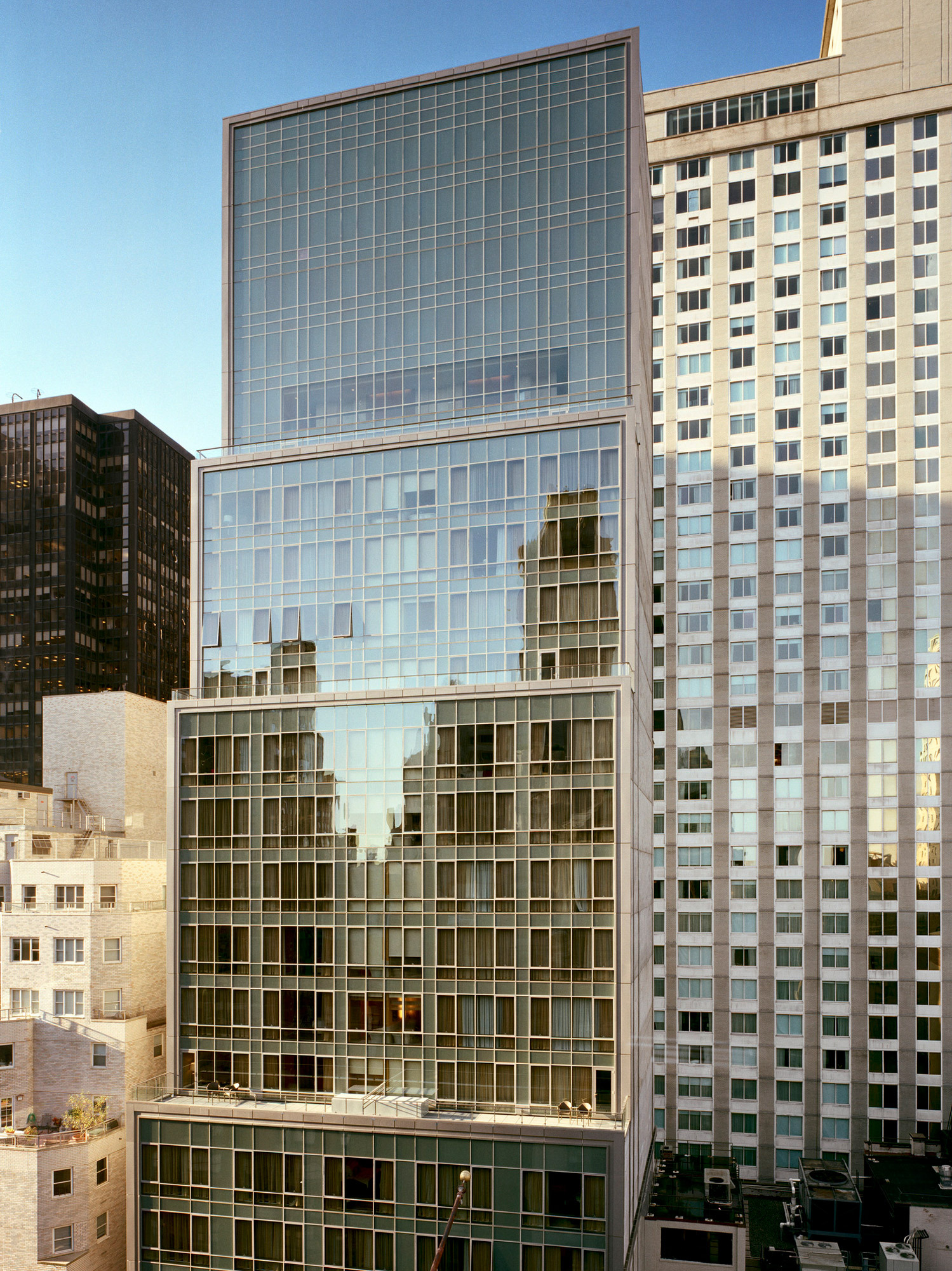 Modern urban office building facade showcasing a juxtaposition of reflective glass curtain walls and traditional concrete, enhancing the verticality and lightness of contemporary architectural design.