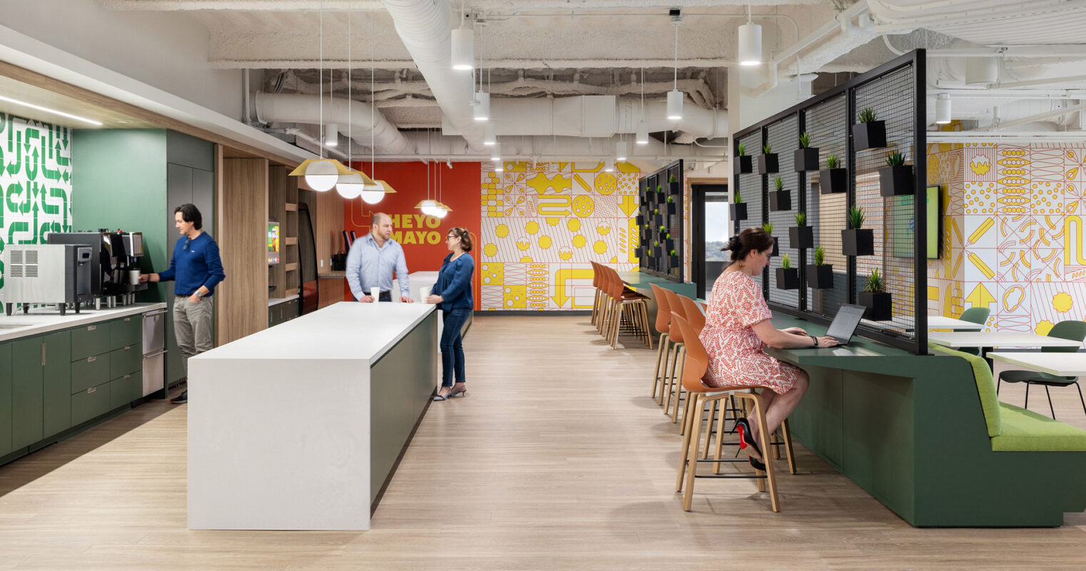 An office with people working diligently at desks and tables, focused on their tasks and collaborating with colleagues.