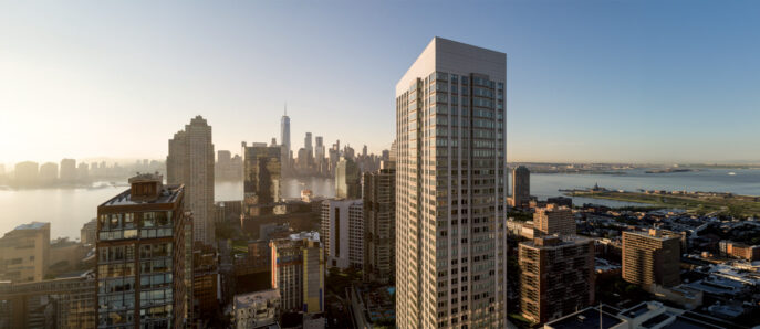 Sunset bathes a modern skyscraper and surrounding cityscape, highlighting the contrast between the glass facade and the urban environment, with a view of a distant iconic tower.