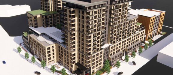 Aerial view of a modern multi-story residential building with mixed-material facade, expansive balconies, and integrated green spaces, surrounded by water on a clear day.