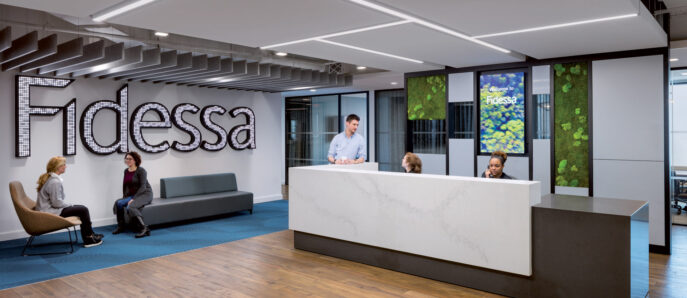 Modern corporate reception area featuring a sleek, white curved desk with gray accents, set against a backdrop with the company's name in bold relief letters. Ambient lighting from linear fixtures enhances the welcoming space, complemented by minimalist seating and vibrant digital displays of greenery.