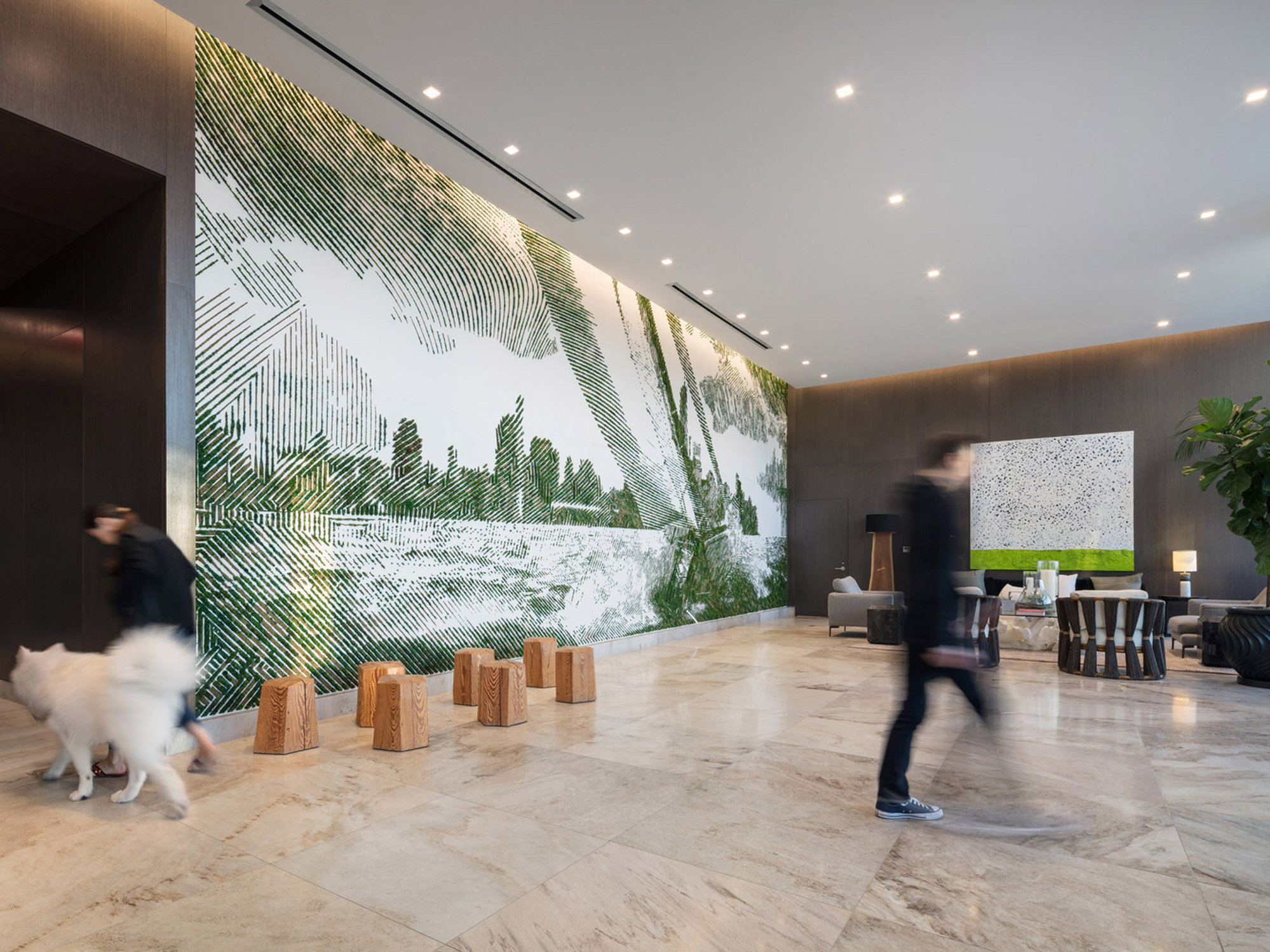 Sleek, expansive lobby featuring a high-contrast green and white abstract wall mural, polished stone flooring, recessed lighting, and natural wood panels. Contemporary seating and wooden stump accents provide an organic touch juxtaposed against the mural's modernity.