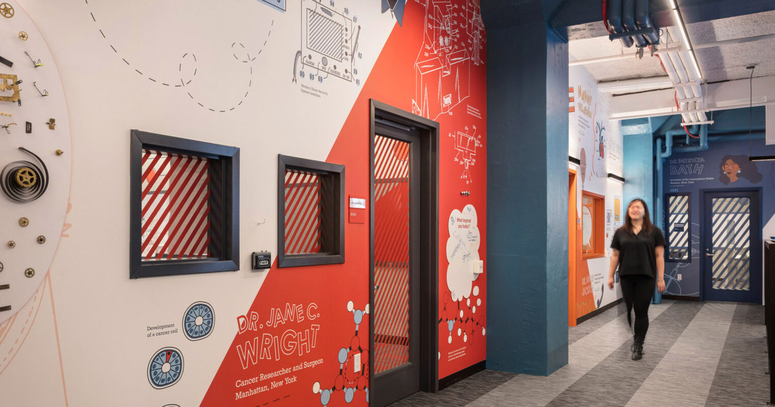 Vibrantly themed educational corridor with interactive walls featuring timelines and illustrations, contrasted by industrial ceiling elements and minimalist lighting, inviting active learning and engagement.