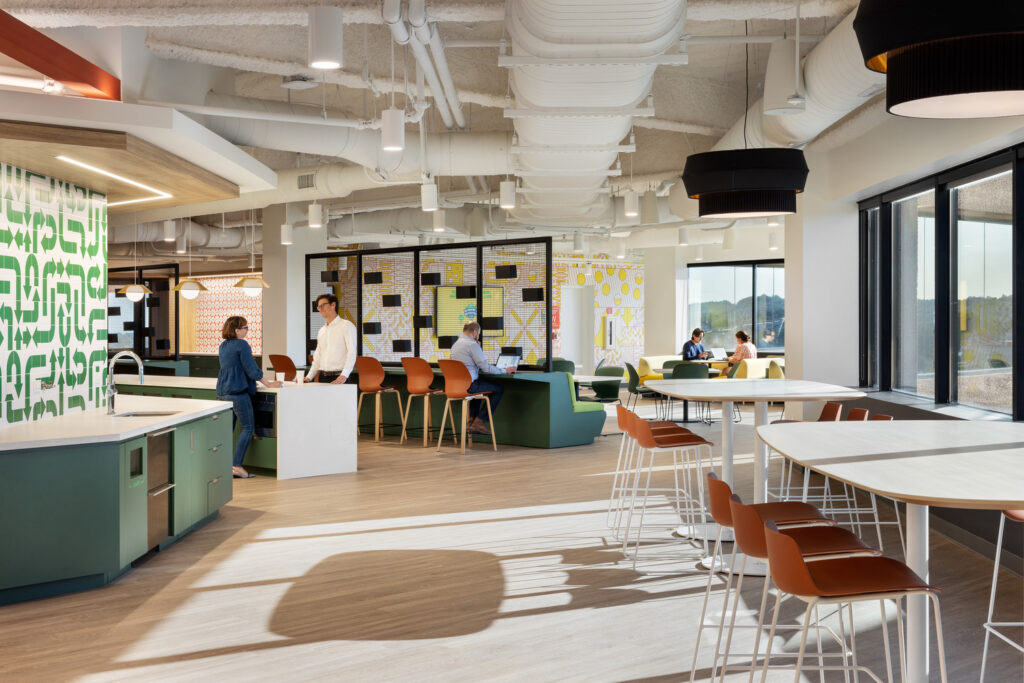 An office with people working diligently at desks and tables, focused on their tasks and collaborating with colleagues.
