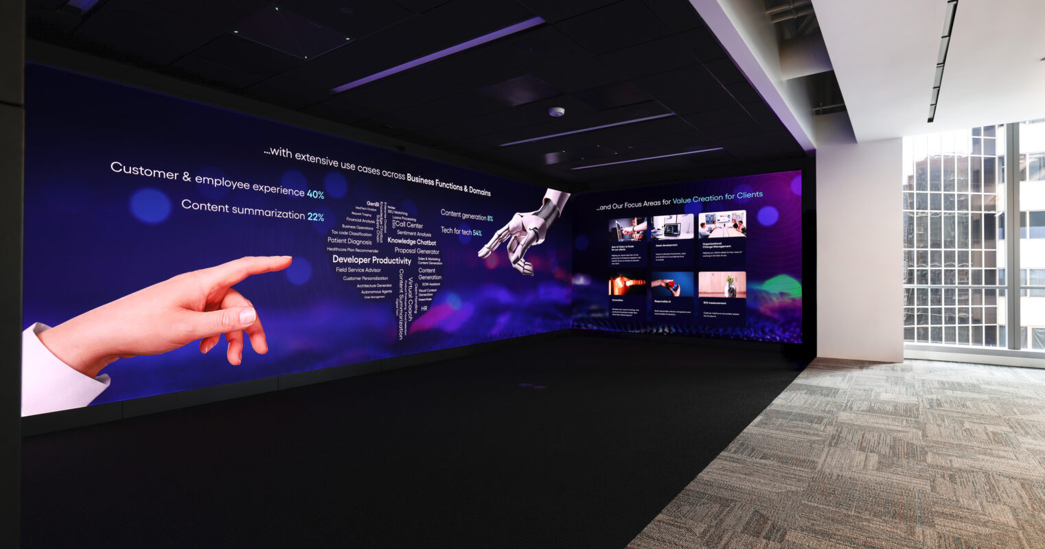 A modern corporate presentation room features a striking large-scale wall display showcasing interactive multimedia content. Bold graphics and data visualization promote customer experience and developer solutions. The sleek, dark flooring and ambient lighting create an inviting yet professional atmosphere, enhancing engagement and collaboration during presentations.