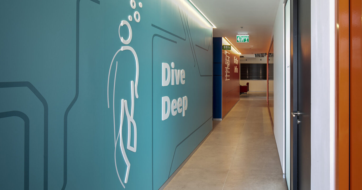 Vibrant corridor featuring a bold teal wall adorned with minimalist graphics illustrating a diver and bubbles. The sleek, modern flooring contrasts with the colorful accent walls, enhancing the contemporary aesthetic. The design emphasizes a theme of exploration and adventure, creating an engaging atmosphere in the interior space.