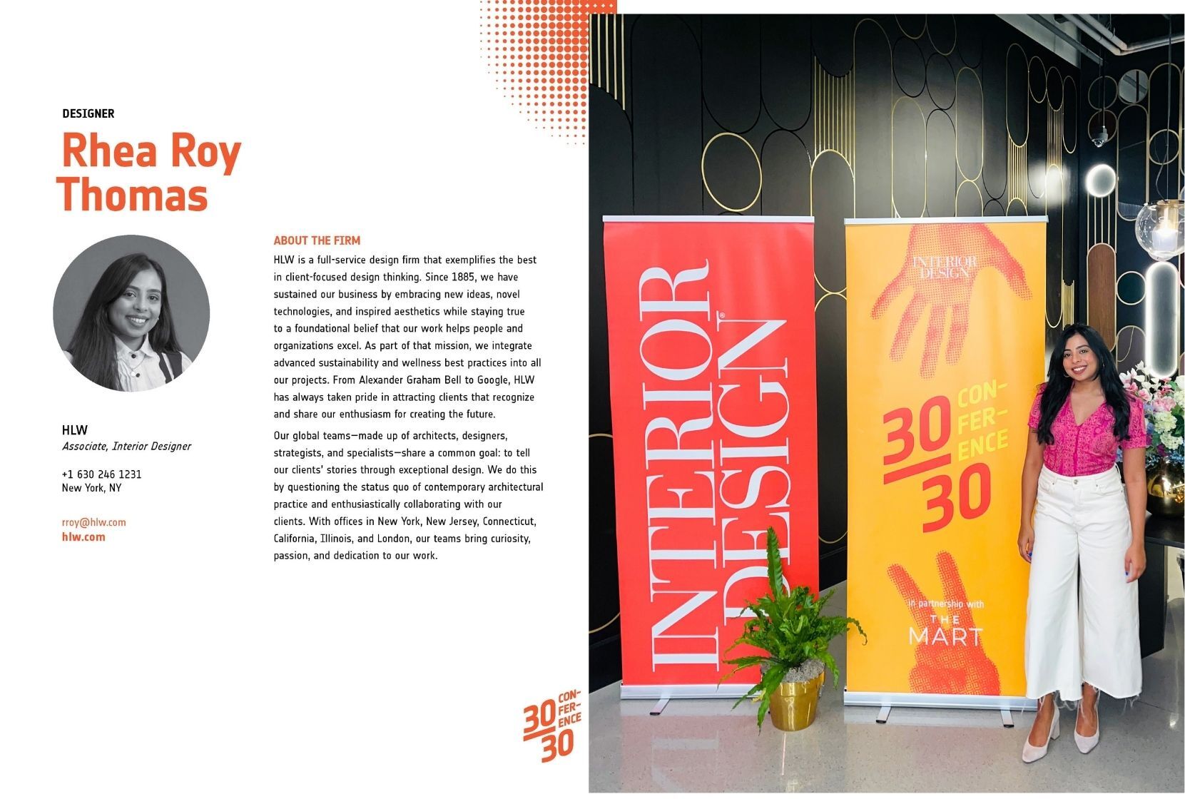 Interior designer Rhea Roy Thomas stands confidently beside a vibrant display at a design conference. The backdrop features bold graphics announcing the event, highlighting innovation in sustainable design. Her professional attire complements the creative atmosphere, showcasing a commitment to contemporary trends and environmental responsibility in interior design.